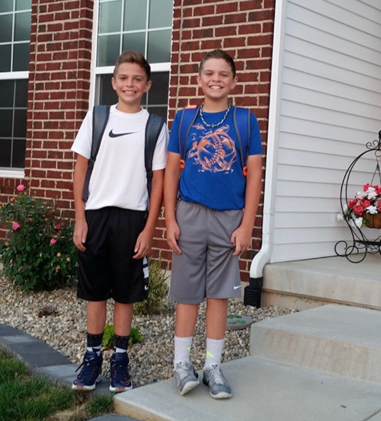 Andrew and Michael as children, standing together with backpacks