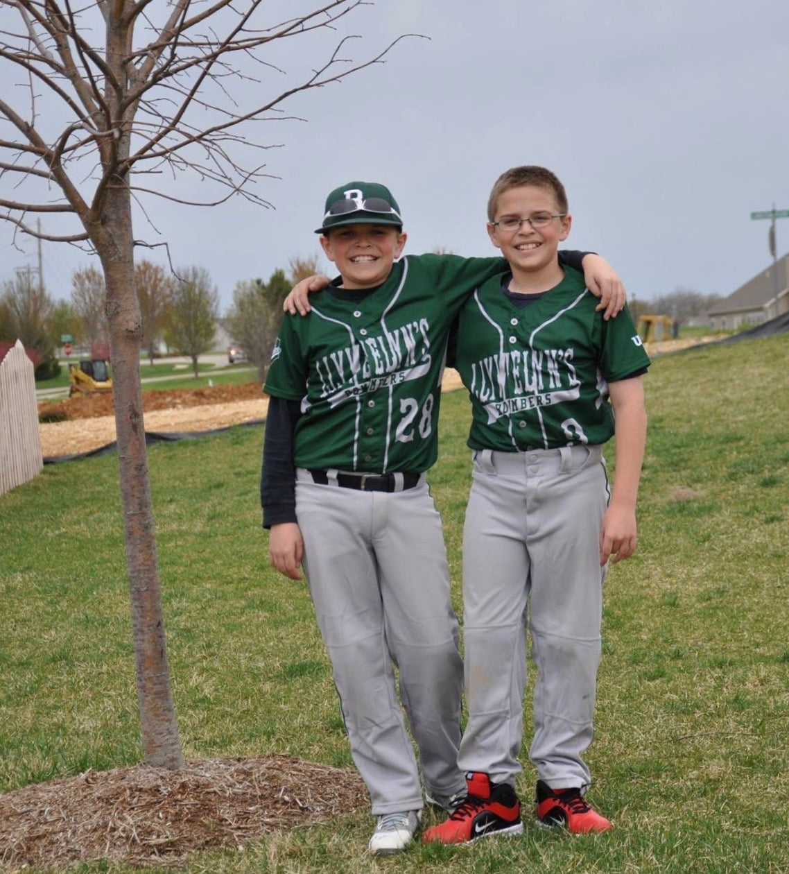 Andrew and Michael as children in green baseball uniforms